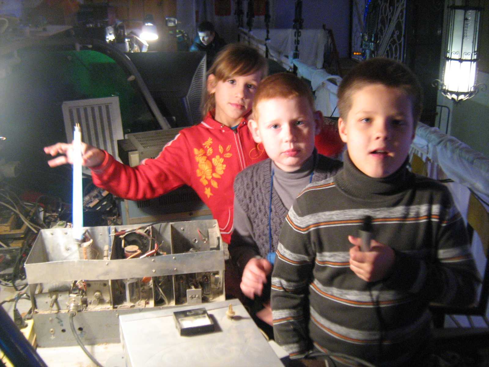 Левина Кира (держит горящую люминесцентную лампу у катушки П-контура СВ радиопередатчика), Бондарь Никита, Малов Арсений (с микрофоном).